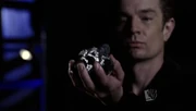 Fine holds the silver kryptonite in his hand.
