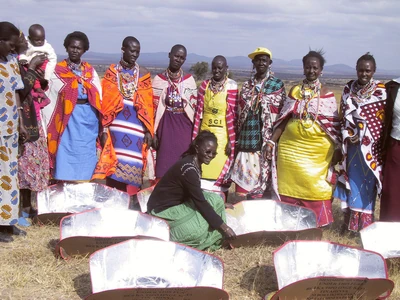Women in Kajido, Kenya stand with their CooKit solar cookers.
