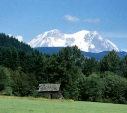 An old cabin and the top of Mount Rainier in the background.